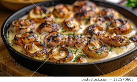 Grilled scallops in creamy garlic sauce garnished with parsley in black skillet 122570603