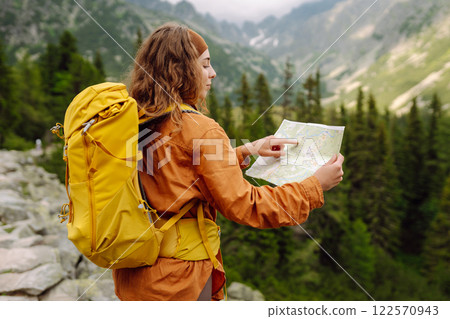 The adventure begins! Beautiful woman traveler with a yellow backpack, holds a map. Vacation concept 122570943