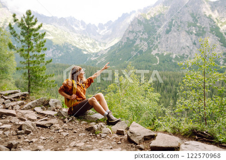 Young traveler woman with a yellow backpack on a cliff. Sports concept, traveler. Active lifestyle. Young traveler woman with a yellow backpack on a cliff. Sports concept, traveler. Active lifestyle. 122570968