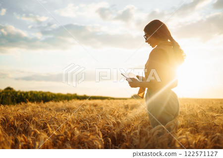 Young Female farmer with tablet in the field. Agriculture, gardening, business or ecology concept. Young Female farmer with tablet in the field. Agriculture, gardening, business or ecology concept. 122571127