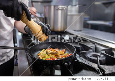 Chef adding spices to grilled vegetables Chef adding spices to grilled vegetables 122571190