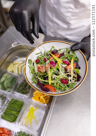 Professional chef adding final touches to a vibrant salad Professional chef adding final touches to a vibrant salad 122571191