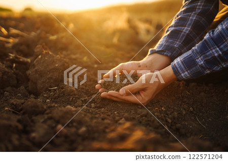 Farm owner checks quality of soil with his hands with tablet and checks fertility before sowing. 122571204