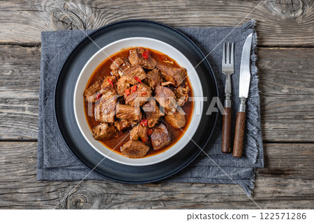 beef stew in a white bowl on rustic wooden table 122571286
