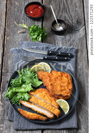 Pork Milanese with lettuce and lemon on a plate 122571293