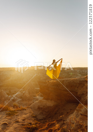 Woman stands on mountain with flying air balloons on background. Tourist Turkish region Cappadocia. 122571819