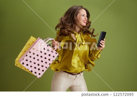 smiling trendy woman using smartphone against green background smiling trendy woman using smartphone against green background 122572095