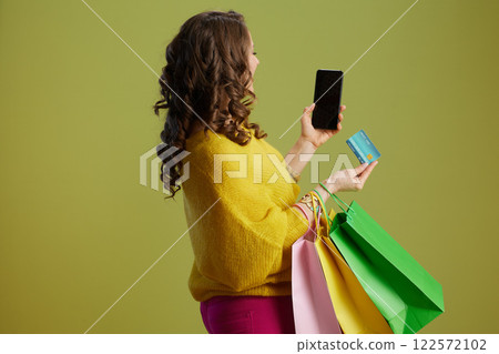 woman showing smartphone blank screen against green woman showing smartphone blank screen against green 122572102