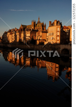 Golden hour cityscape with historic buildings reflected in calm water 122572355