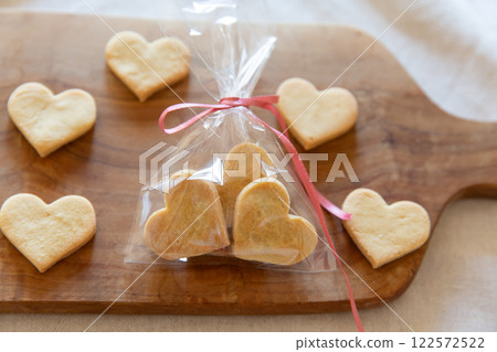 Wrapped homemade heart-shaped cookies on a wooden board 122572522