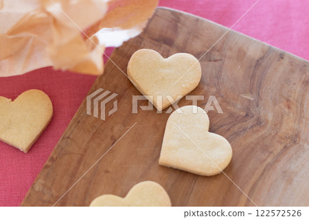 Heart-shaped homemade cookies lined up on a wooden board 122572526