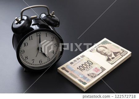 Clock and stack of bills on black background 122572718