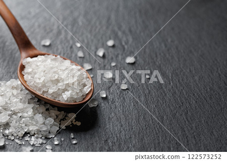 sea salt in spoon on black stone background sea salt in spoon on black stone background 122573252