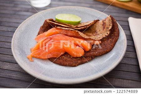 Salted salmon fillet with buckwheat pancakes and lime 122574889