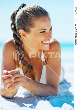 Happy young woman laying on beach and looking on copy space Happy young woman laying on beach and looking on copy space 122575008