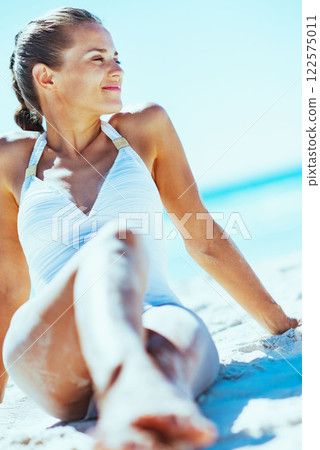 Young woman in swimsuit enjoying sitting on beach Young woman in swimsuit enjoying sitting on beach 122575011