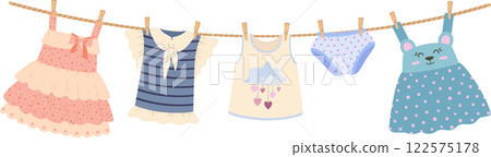 Clean baby clothes hanging on a clothesline, drying in the warm sunlight. The collection features dresses, a shirt, a tank top, and adorable panties, creating a charming scene Clean baby clothes hanging on a clothesline, drying in the warm sunlight. The collection features dresses, a shirt, a tank top, and adorable panties, creating a charming scene 122575178
