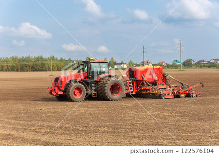 A tractor with a pneumatic seeder attached sows A tractor with a pneumatic seeder attached sows 122576104