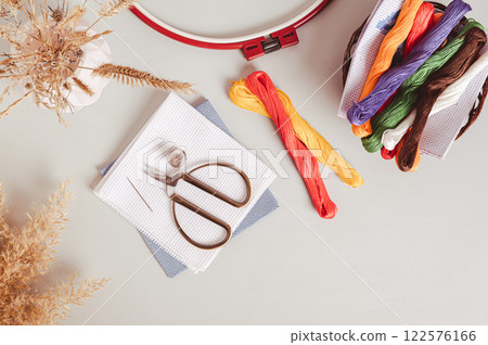 Canvas, embroidery floss, scissors, needle, thimble and cross stitch hoop on table top view Canvas, embroidery floss, scissors, needle, thimble and cross stitch hoop on table top view 122576166