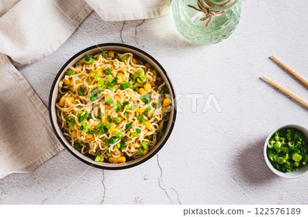 Instant noodles with corn and green onions in a bowl on the table top view Instant noodles with corn and green onions in a bowl on the table top view 122576189