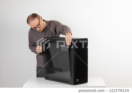 Man removing  tempered-glass left panel  from  PC case, empty big tower, chassis. 122576529