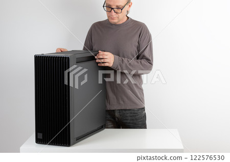Man putting to table heavy PC case, weight 15,8 kg, empty big tower, chassis. 122576530