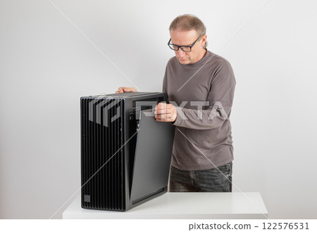 Man removing  metal right  panel  from  PC case, empty big tower, chassis. 122576531