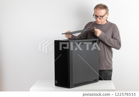 Man removing  top panel with dust filter from  PC case, empty big tower, chassis. Under top panel is place for 420 mm radiator for AIO cooling 122576533
