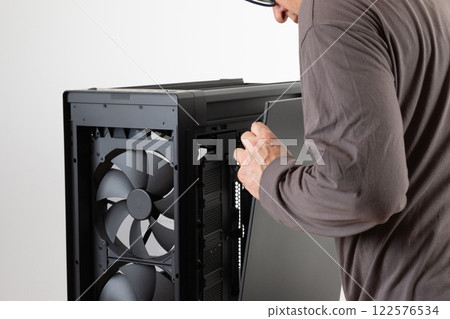 Man removing  metal right  panel  from  PC case, empty big tower, chassis. PC case without top and front panel. 122576534