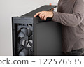 Man installing  top panel with dust filter from  PC case, empty big tower, chassis. Under top panel is place for 420 mm radiator for AIO cooling 122576535