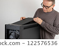 Man installing  top panel with dust filter to  PC case, empty big tower, chassis. Under top panel is place for 420 mm radiator for AIO cooling 122576536