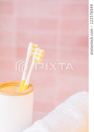 Two yellow toothbrushes in holder in bathroom on pink background Two yellow toothbrushes in holder in bathroom on pink background 122576849