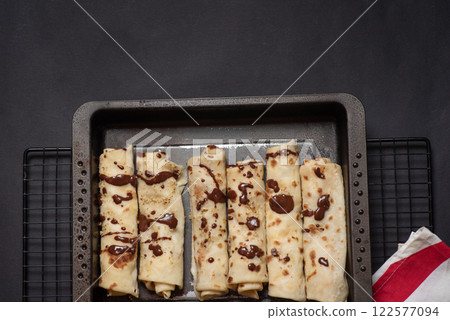 Delicious Chocolate Drizzled Crepe on Black Tray 122577094