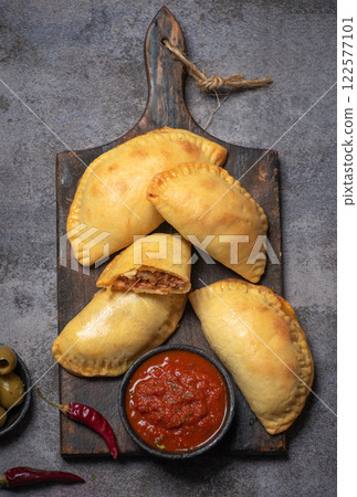 Golden Empanadas with Salsa on a Wooden Board Golden Empanadas with Salsa on a Wooden Board 122577101