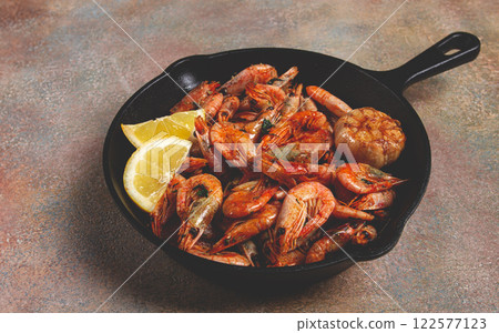 Fried shrimps, in a cast-iron pan, shrimps for beer, in a newspaper, on a gray table, there are no people, 122577123