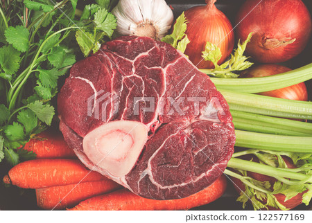 knuckle on the bone, raw meat for ossobuco, with vegetables, in a basket , ingredients for cooking ossobuco, top view, no people, 122577169