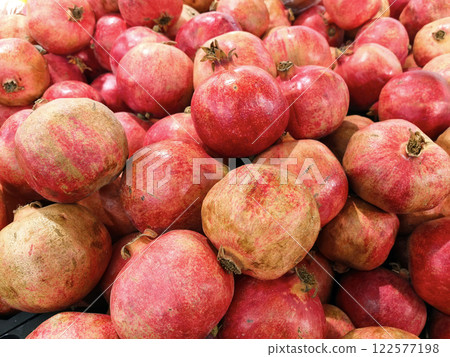 Pomegranates on the market on the counter. Sale of fruits and berries. Background, pattern with fruits, berries, pomegranates. Group of pomegranates. Pomegranate background. Healthy food 122577198
