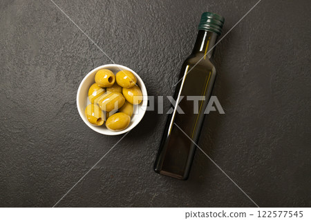Olives and olive oil in bowl with bottle of olive oil on dark background. Mockup for package. Copy space. 122577545