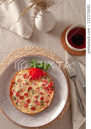 Fried omelette with tomatoes, sausages and fresh herbs for the perfect breakfast 122578892