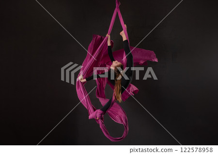 Girl performs aerial silk routine with pink fabric in a stunning display Girl performs aerial silk routine with pink fabric in a stunning display 122578958