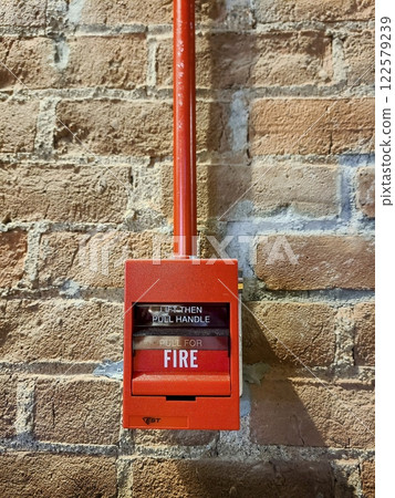 Red Fire Alarm on Rustic Brick Wall Eye-Level View 122579239
