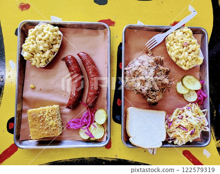 Vibrant American BBQ Feast on Metal Trays Overhead View 122579319