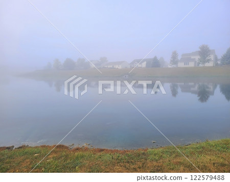 Tranquil Lake Reflection with Misty Suburban Homes at Eye Level Tranquil Lake Reflection with Misty Suburban Homes at Eye Level 122579488