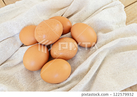 Farm fresh eggs on natural fabric, organic ingredients for cooking in cozy settings. Organic and farm fresh product concept Farm fresh eggs on natural fabric, organic ingredients for cooking in cozy settings. Organic and farm fresh product concept 122579932