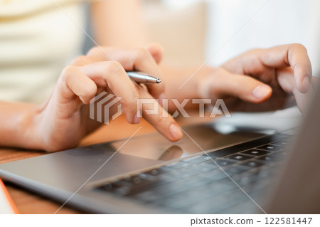 Hands typing on a laptop keyboard with a pen, representing digital work and communication. Hands typing on a laptop keyboard with a pen, representing digital work and communication. 122581447