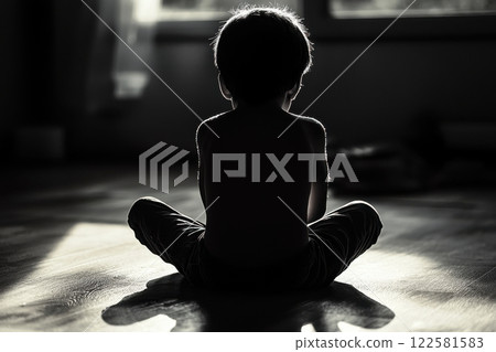 Child in contemplative pose indoor setting black and white photography intimate atmosphere rear view reflection on innocence 122581583