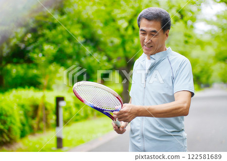 Senior man standing with a tennis racket Senior man standing with a tennis racket 122581689