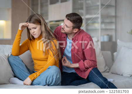 Major quarrel between married couple. Resentful woman, worried man fighting on sofa in living room Major quarrel between married couple. Resentful woman, worried man fighting on sofa in living room 122581703