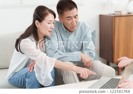 A salesman (businessman/salesman) explaining something to a senior couple using a computer A salesman (businessman/salesman) explaining something to a senior couple using a computer 122581769