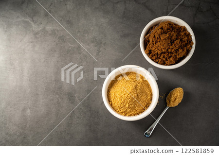 Light brown and dark brown granulated sugar in bowls on dark background, copy space Light brown and dark brown granulated sugar in bowls on dark background, copy space 122581859